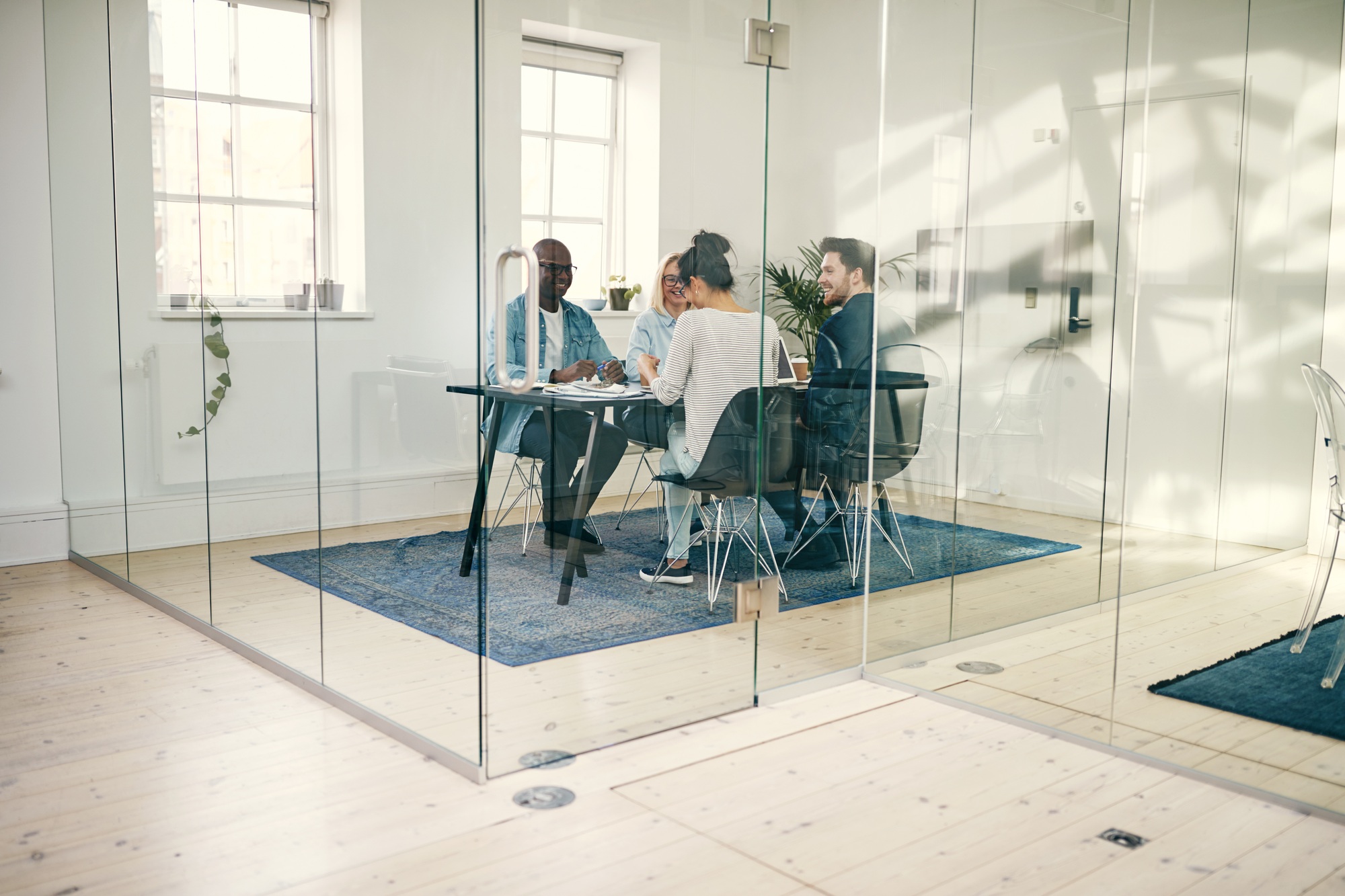 Smiling businesspeople meeting together inside of a glass office